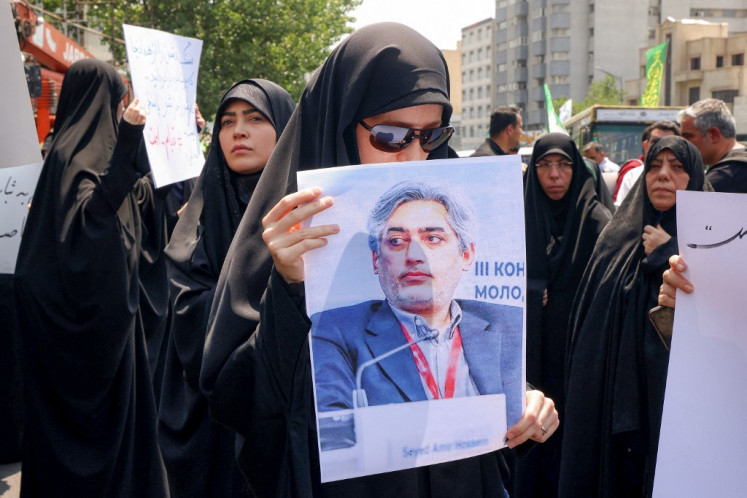 A woman holds a picture of Seyed Amir Hossein Feghhi, the slain head of Iran's Nuclear Science and Technology Research Institute, as people gather for a protest against Israel's wave of strikes on Iran in central Tehran on June 13, 2025. Israel hit about 100 targets in Iran on June 13, including nuclear facilities and military command centers and killing senior figures including the armed forces chief and top nuclear scientists.